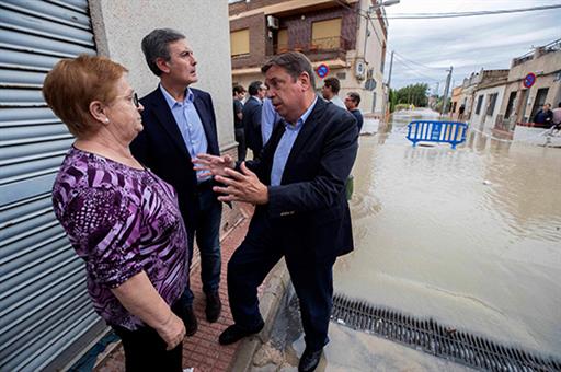 Luis Planas y el secretario de estado de Infraestructuras, Pedro Saura, conversan con una vecina de Molina de Segura