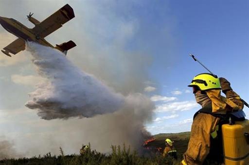 Avión anfibio descargando agua en una zona de incendios activos