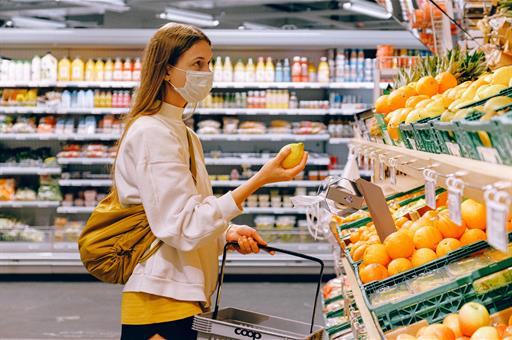 Mujer con mascarilla compra fruta en un supermercado