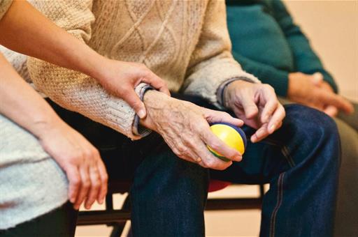 Cuidadora ayuda a una persona mayor a hacer ejercicios con una pelota