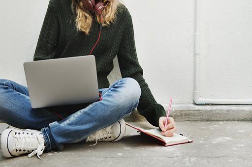 Estudiante con un portátil y un bloc de notas