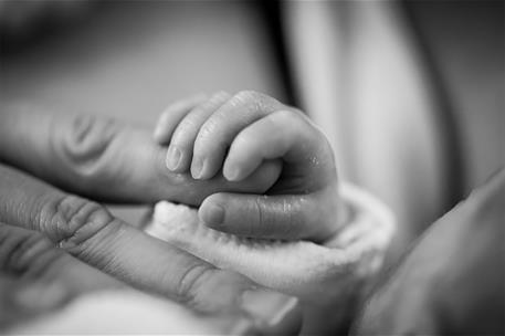 Una mano infantil agarra un dedo de una mano adulta