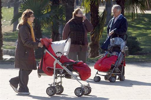 Cuidadoras y cuidadores a cargo de bebés paseando por un parque