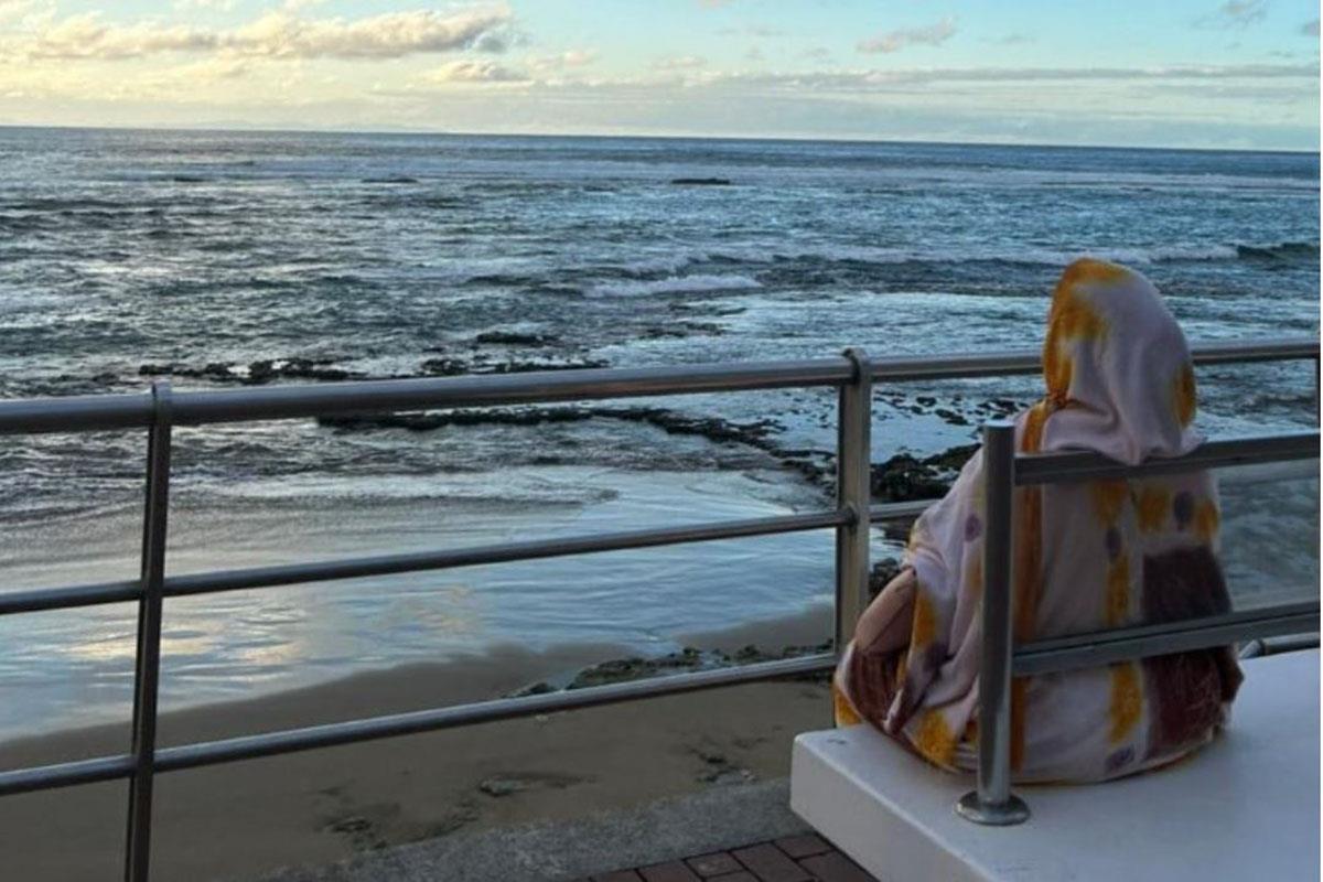 Una mujer migrante mira al mar
