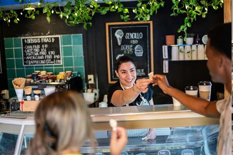 Empleada de heladeria atendiendo a dos clientes