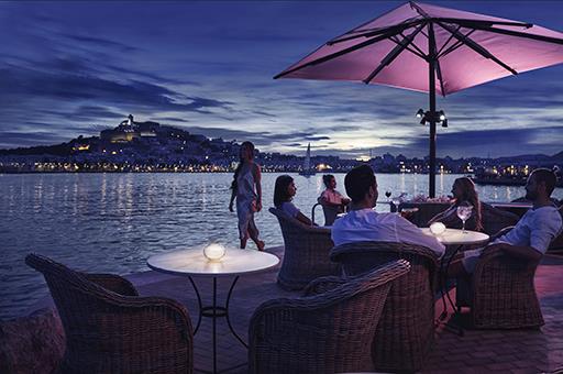Turistas en una terraza al anochecer junto al mar