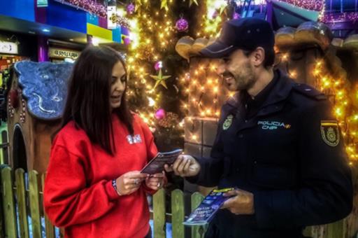 Un agente de la Polica Nacional dndole un folleto a una chica sobre Comercio Seguro