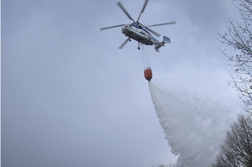 Helicóptero descargando agua sobre un incendio forestal