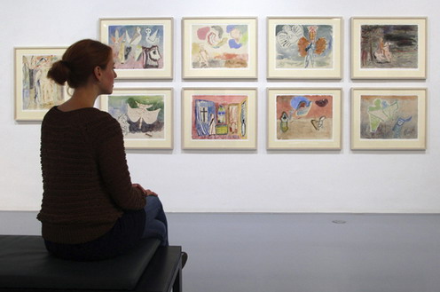 Una mujer observa un conjunto de cuadros