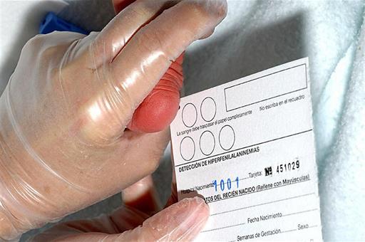 Un trabajador sanitario realiza la prueba del talón a un bebé